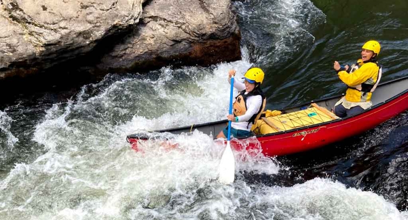 two gap year students paddle a canoe through whitewater on an outward bound expedition in north carolina 